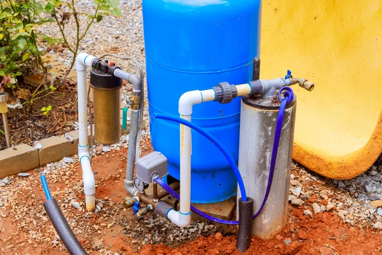Sistema de pressurização de poço instalado em quintal, com tanque azul, filtro e tubulação de PVC, entregue por empresa de poço artesiano no RJ