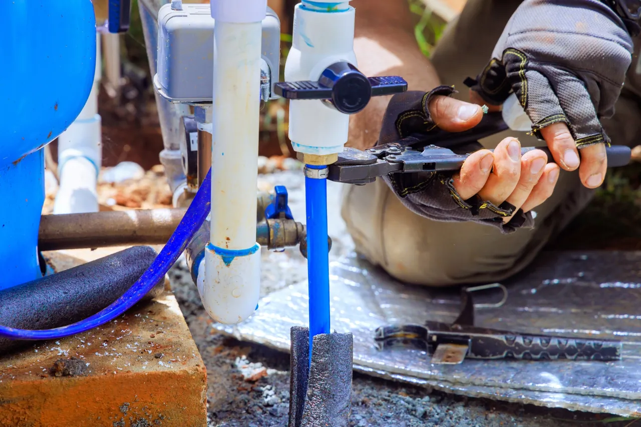 Técnico com alicate em conexão de PVC e tubo azul durante a troca de bomba submersa de poço artesiano no Rio de Janeiro